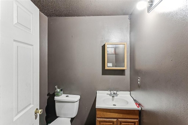 half bathroom with toilet, a textured ceiling, and vanity