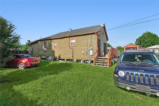 rear view of house with roof with shingles and a lawn