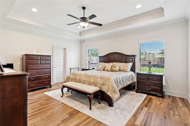 bedroom featuring light hardwood / wood-style floors, a raised ceiling, crown molding, and ceiling fan