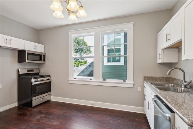 kitchen with appliances with stainless steel finishes, a chandelier, sink, and white cabinets