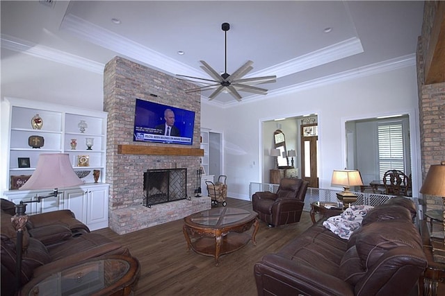 living room with a tray ceiling, a fireplace, wood-type flooring, and ceiling fan