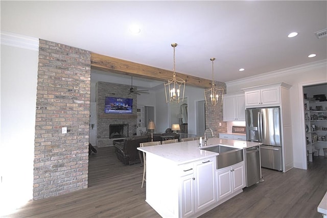 kitchen featuring a fireplace, sink, dark wood-type flooring, and a kitchen island with sink