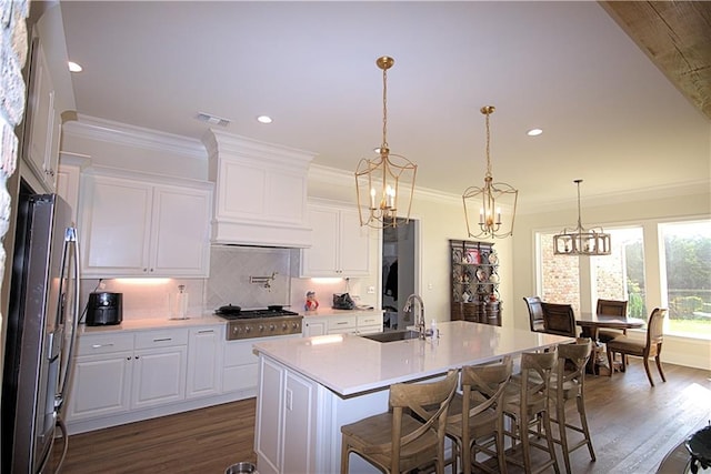 kitchen with white cabinets, dark wood-type flooring, hanging light fixtures, appliances with stainless steel finishes, and sink