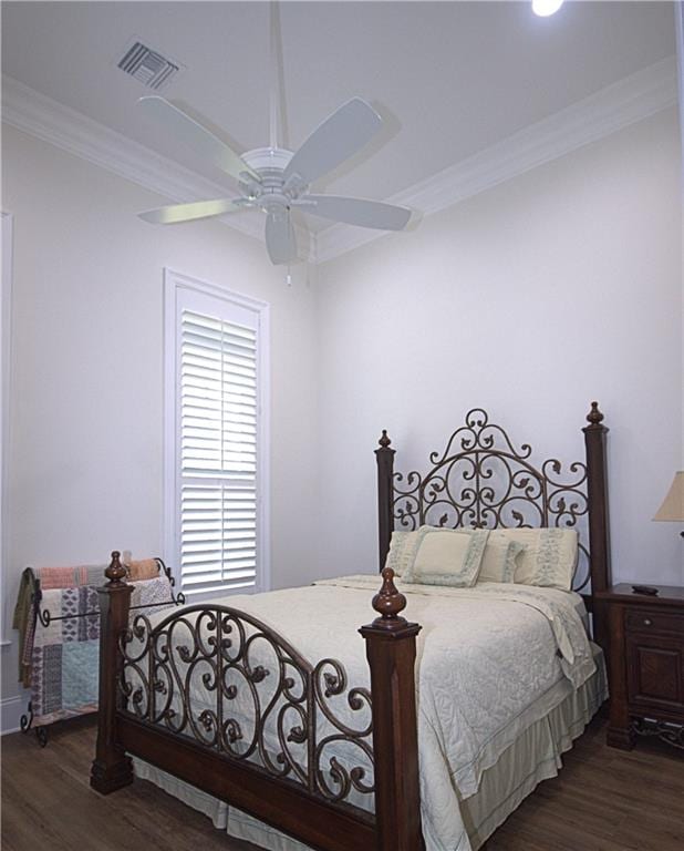 bedroom featuring dark wood-type flooring, ornamental molding, and ceiling fan