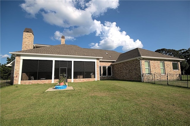 rear view of house featuring a sunroom and a lawn