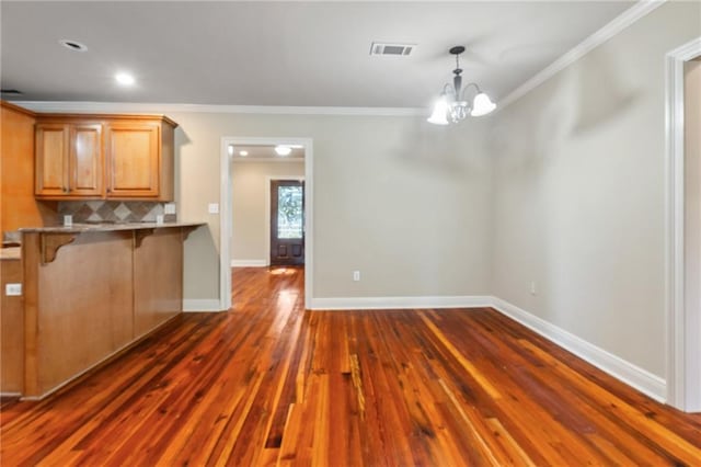 kitchen with a breakfast bar area, dark hardwood / wood-style floors, pendant lighting, and ornamental molding