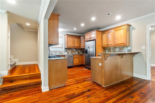 kitchen featuring backsplash, crown molding, appliances with stainless steel finishes, and dark wood-type flooring