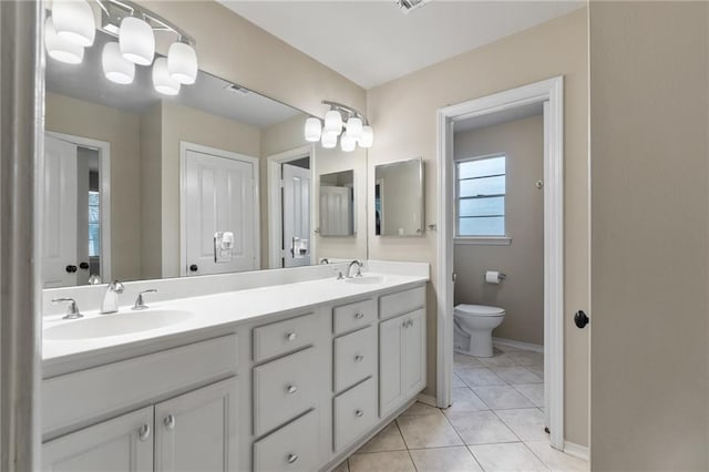 bathroom featuring tile patterned floors, toilet, and dual bowl vanity