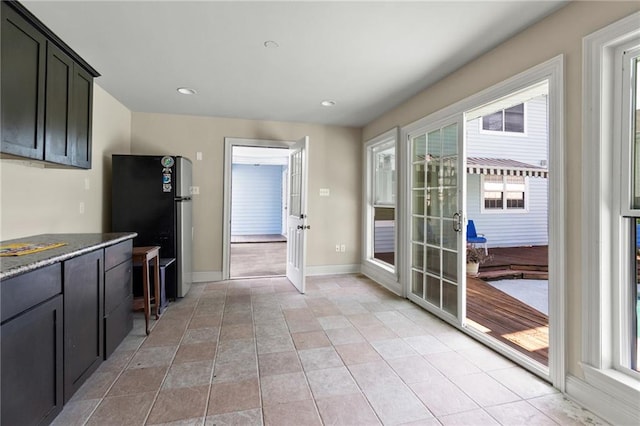 kitchen with light tile patterned flooring, black refrigerator, and plenty of natural light