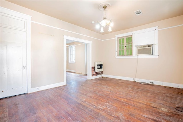 empty room with a notable chandelier, heating unit, wood-type flooring, and cooling unit