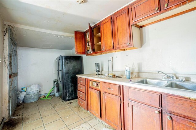 kitchen with black fridge, light tile patterned floors, and sink