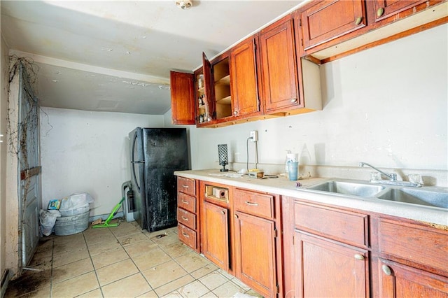 kitchen with light tile patterned flooring, sink, and black refrigerator