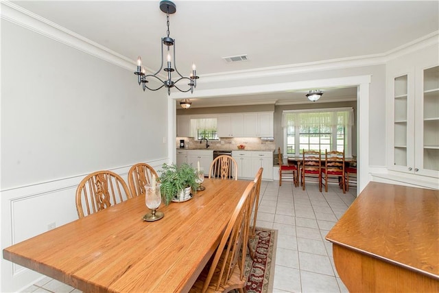 dining space with a notable chandelier, sink, light tile patterned flooring, and crown molding