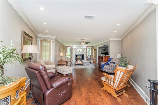 living room with hardwood / wood-style flooring, ornamental molding, a fireplace, and ceiling fan