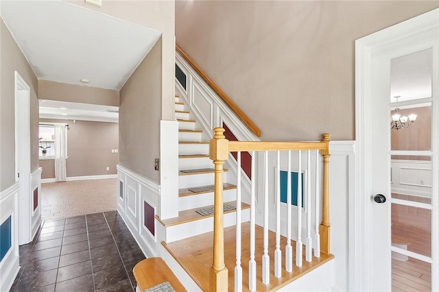 stairs featuring a notable chandelier and dark tile patterned floors