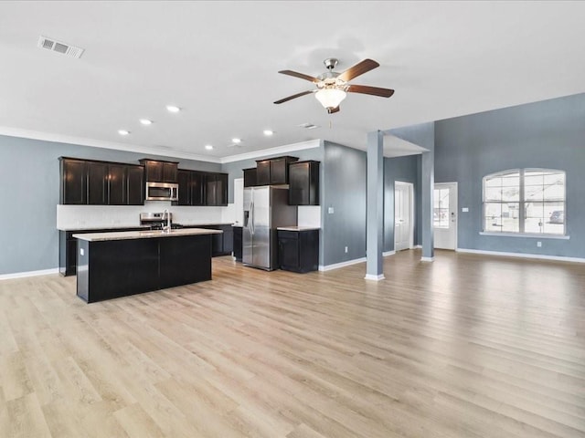 kitchen with a center island with sink, light hardwood / wood-style flooring, stainless steel appliances, ceiling fan, and dark brown cabinetry