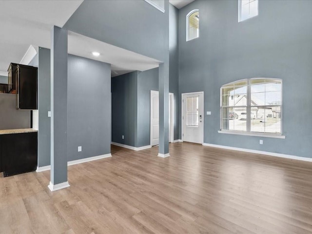 unfurnished living room featuring light wood-type flooring and a high ceiling