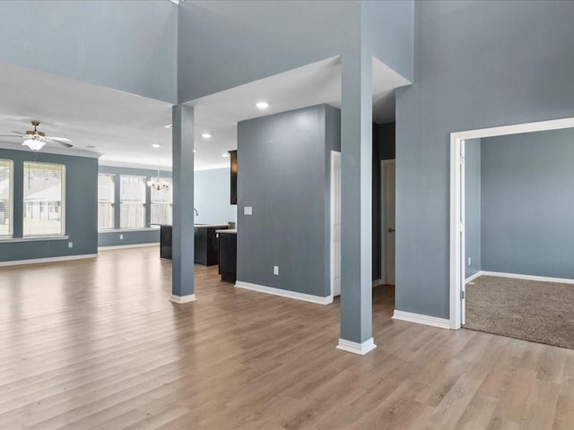 interior space with hardwood / wood-style floors, ceiling fan with notable chandelier, and a towering ceiling