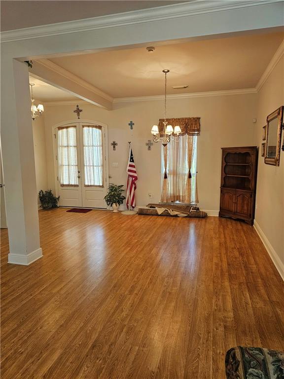 669 Lake Iberville Ct, Ponchatoula, LA 70454 - unfurnished living room with a chandelier, wood finished floors, french doors, ornamental molding, and baseboards
