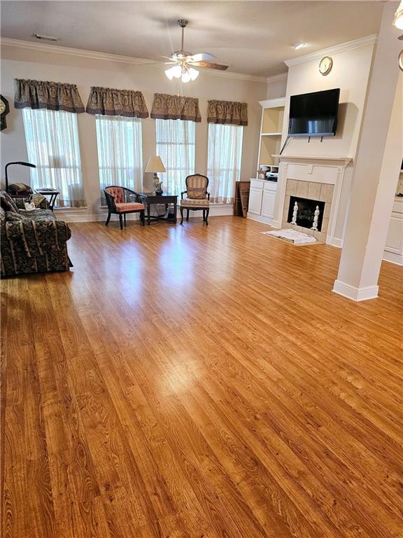 669 Lake Iberville Ct, Ponchatoula, LA 70454 - living room featuring light wood-type flooring, ceiling fan, ornamental molding, a tile fireplace, and baseboards