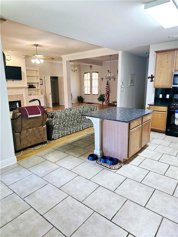 669 Lake Iberville Ct, Ponchatoula, LA 70454 - kitchen featuring black gas stove, stainless steel microwave, dark countertops, open floor plan, and ceiling fan