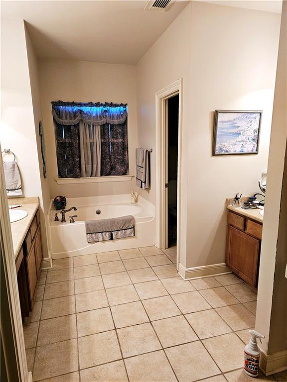 669 Lake Iberville Ct, Ponchatoula, LA 70454 - bathroom featuring tile patterned flooring, vanity, a garden tub, and baseboards