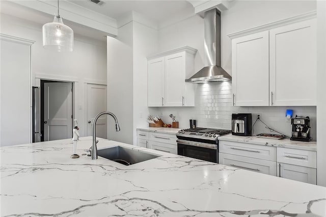 kitchen featuring wall chimney exhaust hood, sink, gas stove, decorative light fixtures, and light stone countertops