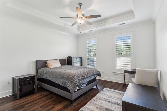 bedroom featuring ceiling fan, dark hardwood / wood-style flooring, and a tray ceiling