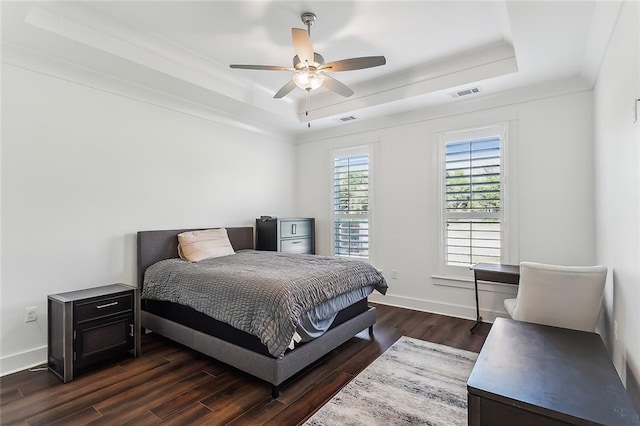 bedroom with dark wood-type flooring, a raised ceiling, and ceiling fan