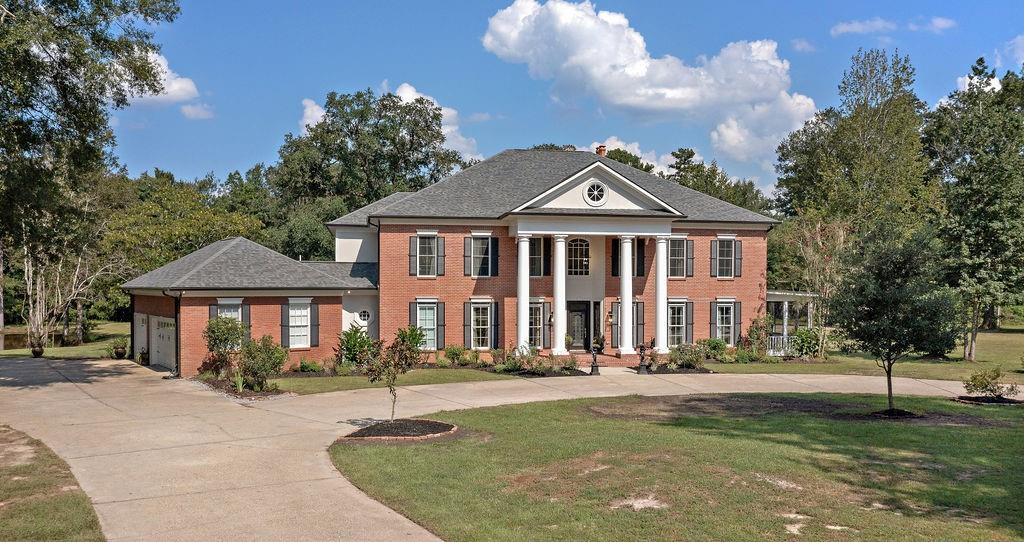 neoclassical / greek revival house featuring a garage and a front yard