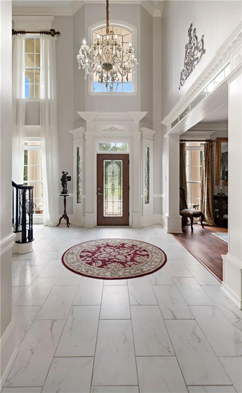 foyer entrance with a high ceiling, ornamental molding, light tile patterned floors, and a healthy amount of sunlight