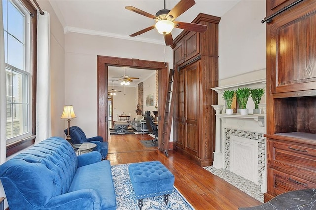 living room with hardwood / wood-style flooring, ceiling fan, ornamental molding, and a wealth of natural light