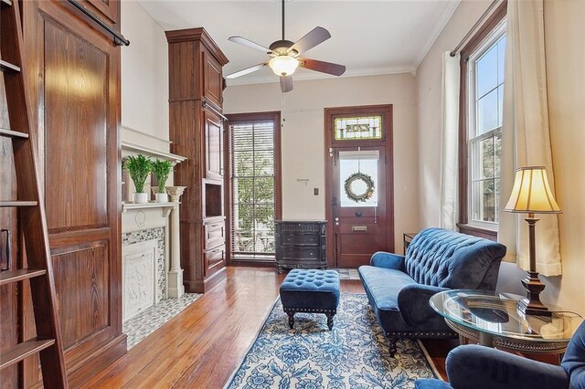 interior space with ceiling fan, a fireplace, hardwood / wood-style flooring, and crown molding