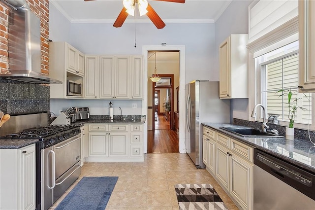 kitchen with appliances with stainless steel finishes, sink, dark stone counters, crown molding, and wall chimney range hood