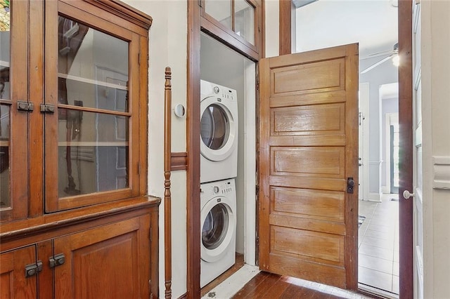 laundry room with stacked washer and dryer and dark wood-type flooring