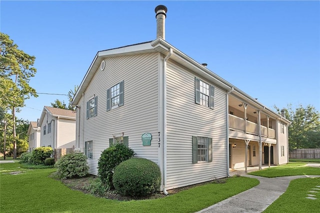 view of side of property with a balcony and a lawn