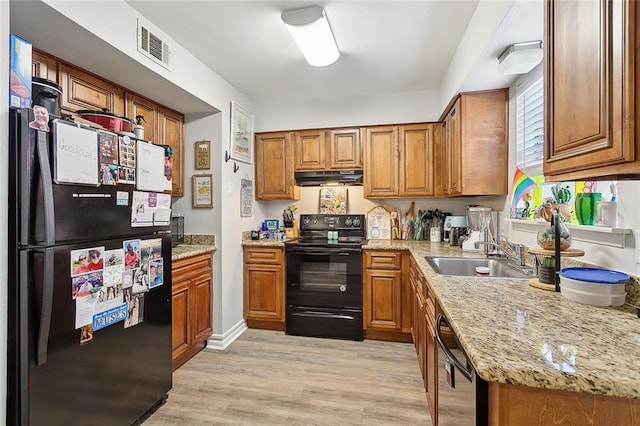 kitchen with black appliances, sink, light stone countertops, and light hardwood / wood-style floors