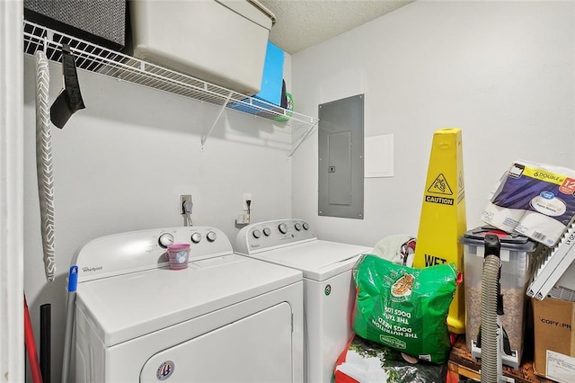 laundry room with washing machine and clothes dryer, a textured ceiling, and electric panel