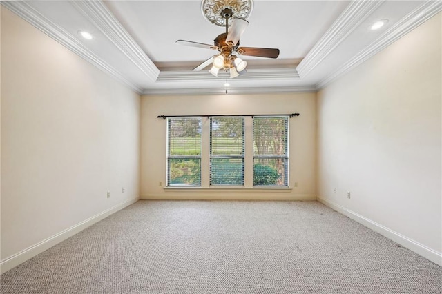 spare room with ceiling fan, a tray ceiling, light carpet, and ornamental molding