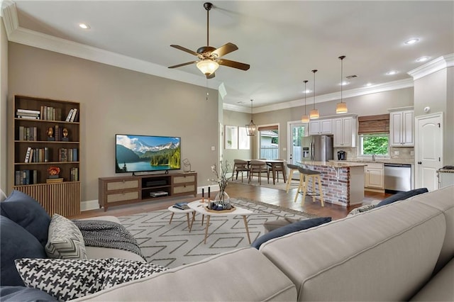 living room featuring ceiling fan, light hardwood / wood-style flooring, sink, and ornamental molding