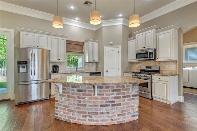 kitchen with tasteful backsplash, washer and clothes dryer, dark hardwood / wood-style flooring, stainless steel appliances, and a kitchen island