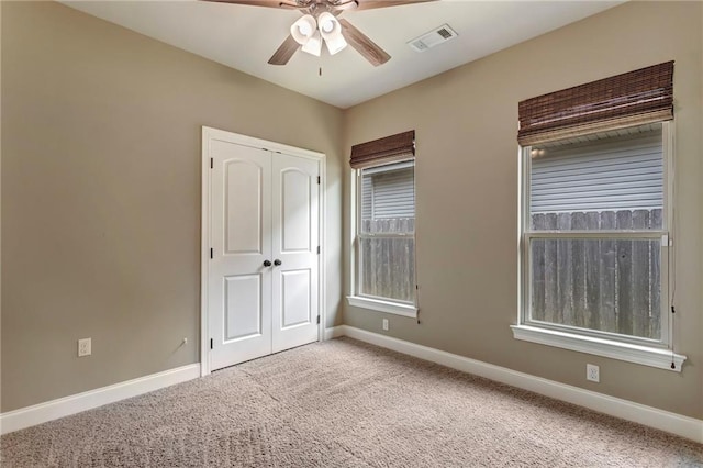 unfurnished bedroom with baseboards, visible vents, carpet, a ceiling fan, and a closet