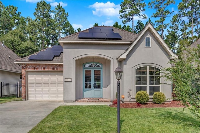 view of front of home featuring concrete driveway, a front lawn, an attached garage, solar panels, and roof with shingles