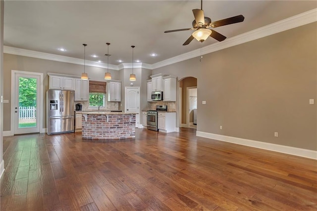 unfurnished living room featuring ceiling fan, wood-type flooring, and ornamental molding