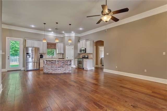 unfurnished living room featuring arched walkways, dark wood finished floors, baseboards, and ceiling fan