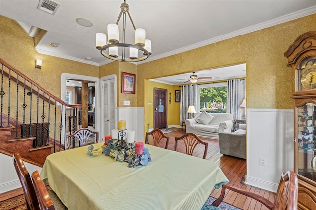 dining space featuring ceiling fan with notable chandelier, ornamental molding, and wood-type flooring