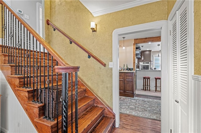 staircase with ornamental molding and hardwood / wood-style flooring