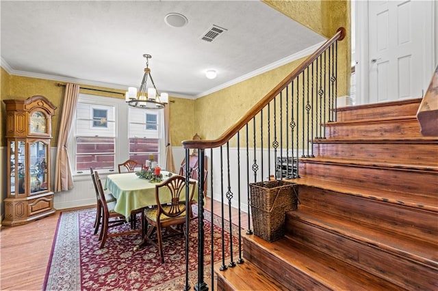 dining space featuring light hardwood / wood-style flooring, ornamental molding, and a chandelier