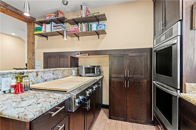 kitchen with stainless steel double oven, light stone counters, gas stovetop, light tile patterned floors, and dark brown cabinetry