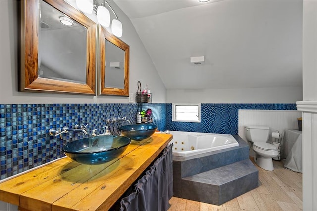 bathroom featuring decorative backsplash, hardwood / wood-style floors, toilet, vaulted ceiling, and vanity